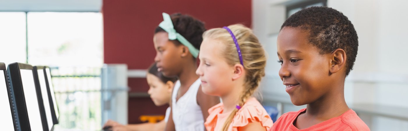 Group of students focused on desktop computers in a classroom, engaged in a computing or digital learning activity