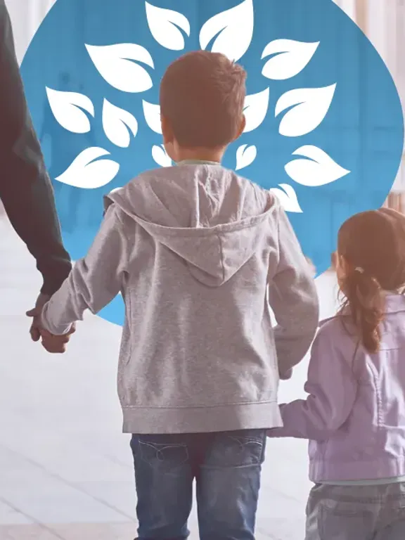 Family of four walking hand in hand through airport with travel bags