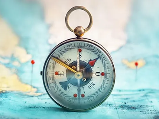 Vintage-style compass placed on a world map, surrounded by red location pins.