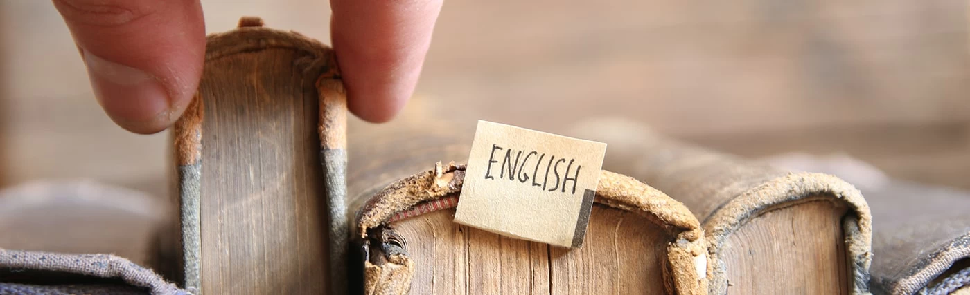 Old English books being pulled from a shelf. 