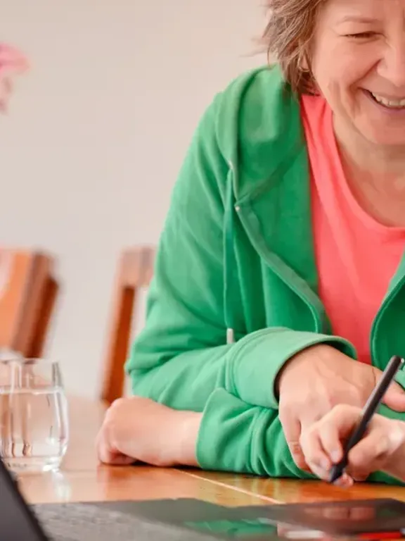 Young girl enjoying a learning activity at home with older adult and laptop
