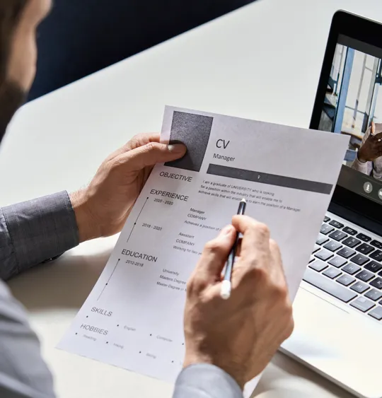 A hiring manager reviews a CV during a remote video interview with a job applicant.