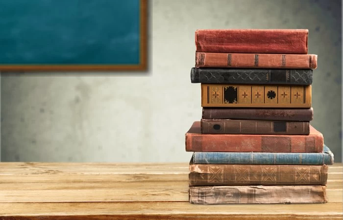 Old English books stacked up on a desk.