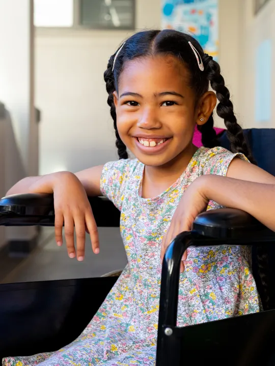 Confident girl smiling in wheelchair in a bright school hallway