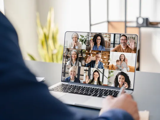 Close up of a laptop screen showing a webinar taking place with multiple people in a call.