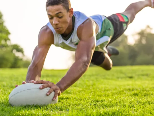 Young male homeschool student in Pretoria diving to score a try in a rugby game, highlighting sports opportunities for homeschoolers.