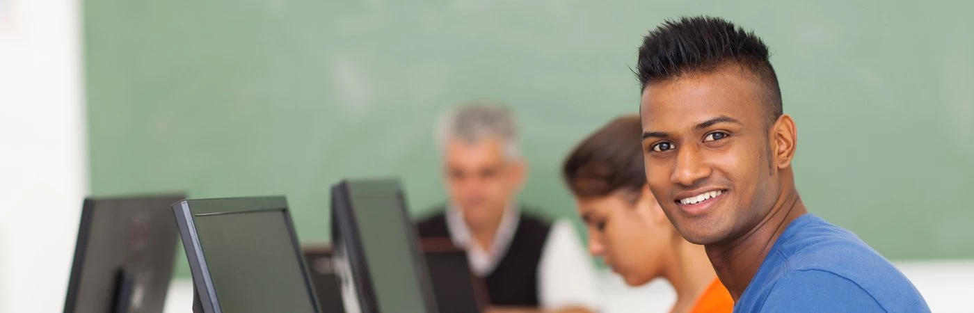An adult learner working on a laptop in a class amongst other adult learners.