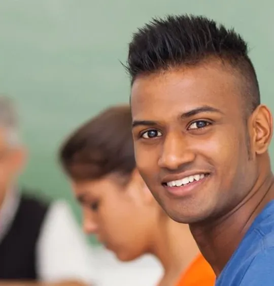 An adult learner working on a laptop in a class amongst other adult learners.