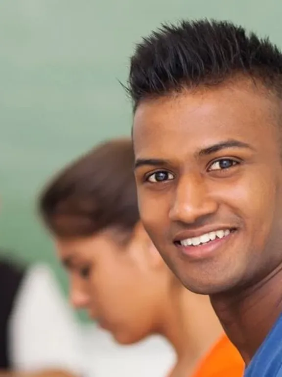 An adult learner working on a laptop in a class amongst other adult learners.