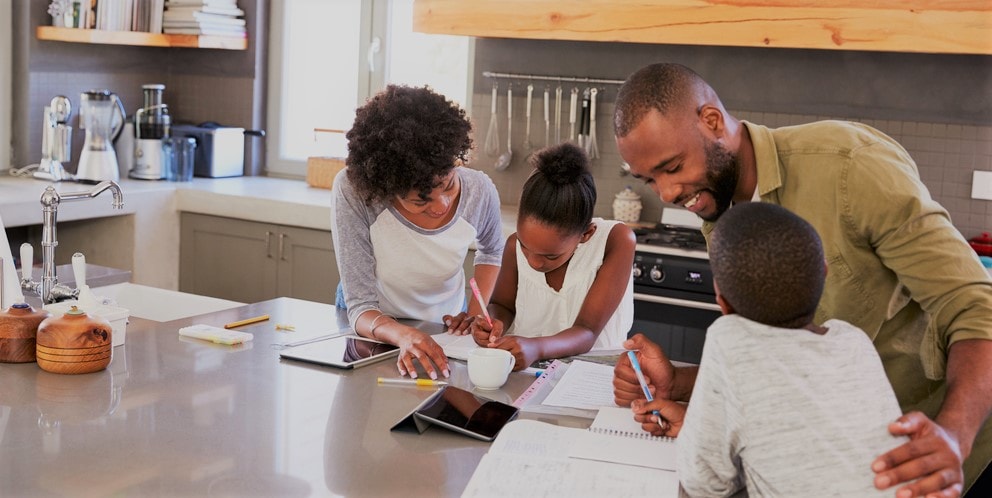 Family of four engaged in homeschool activities around a kitchen island