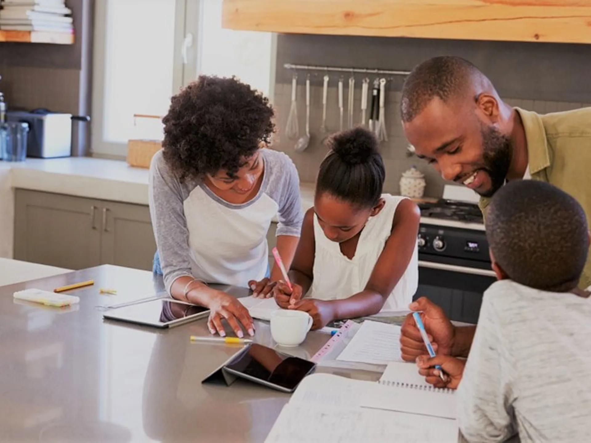 Family of four engaged in homeschool activities around a kitchen island