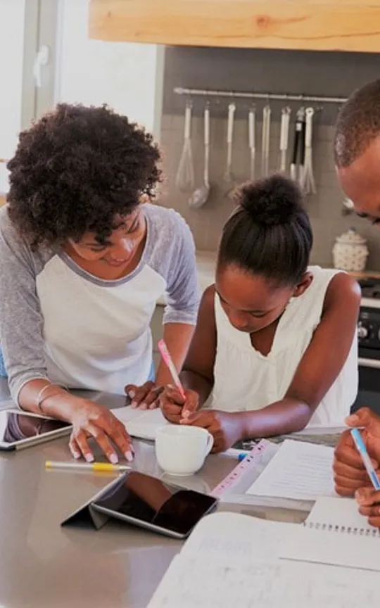 Family of four engaged in homeschool activities around a kitchen island
