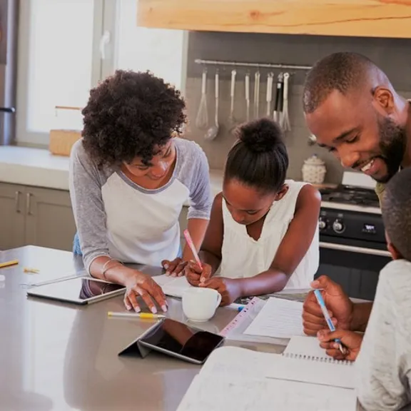Family of four engaged in homeschool activities around a kitchen island