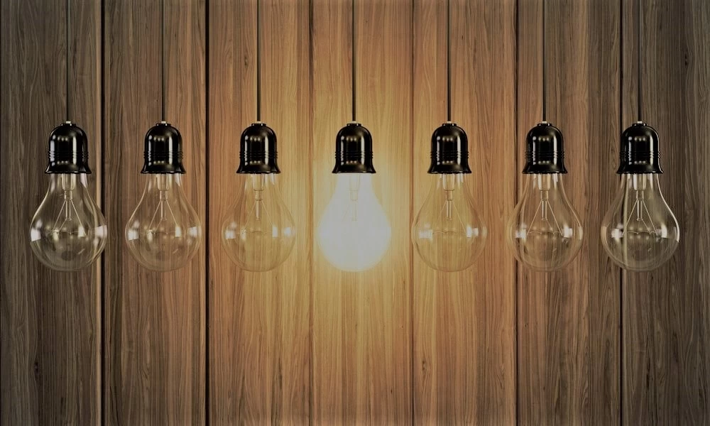 A row of lightbulbs with one of them on.