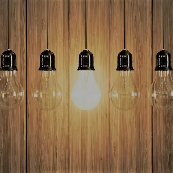 A row of lightbulbs with one of them on.