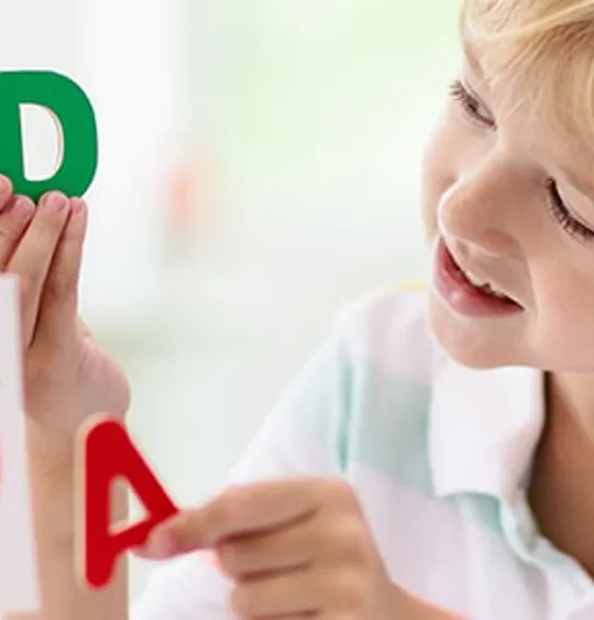 Smiling student with notebook and pen, studying in a cosy home setting with sunlight through window