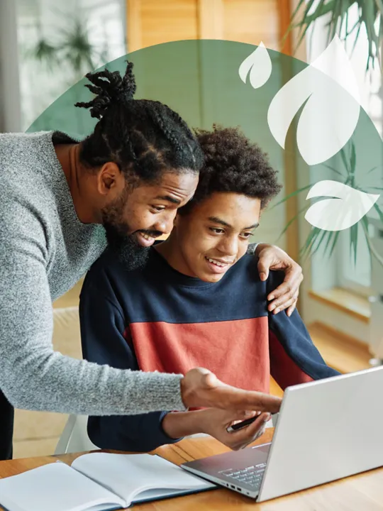 Supportive father helping his son with online learning on a laptop.