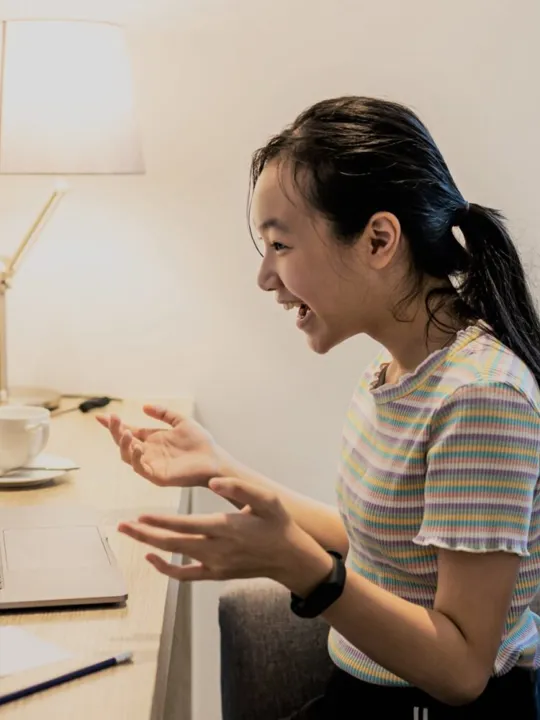 A young girl studying on her laptop at her desk.