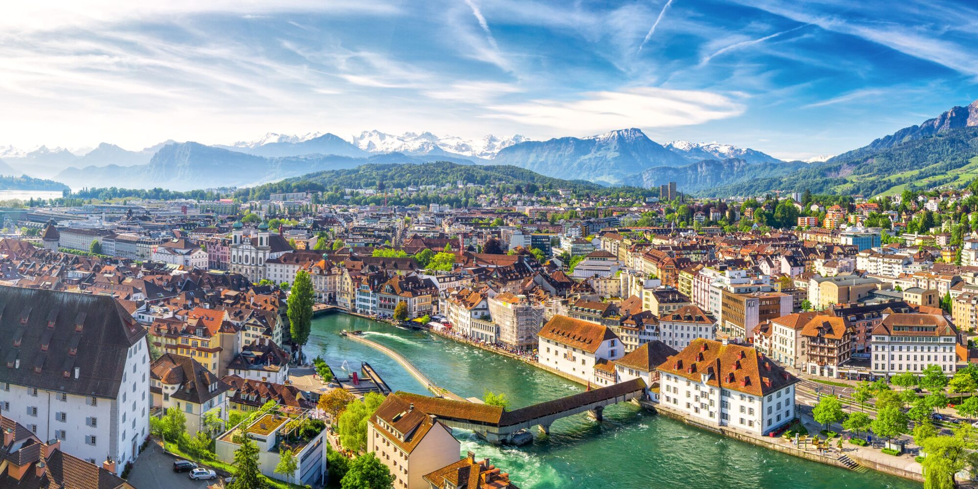 A landscape view of a Swiss village, on a clear day with the sun shining. 