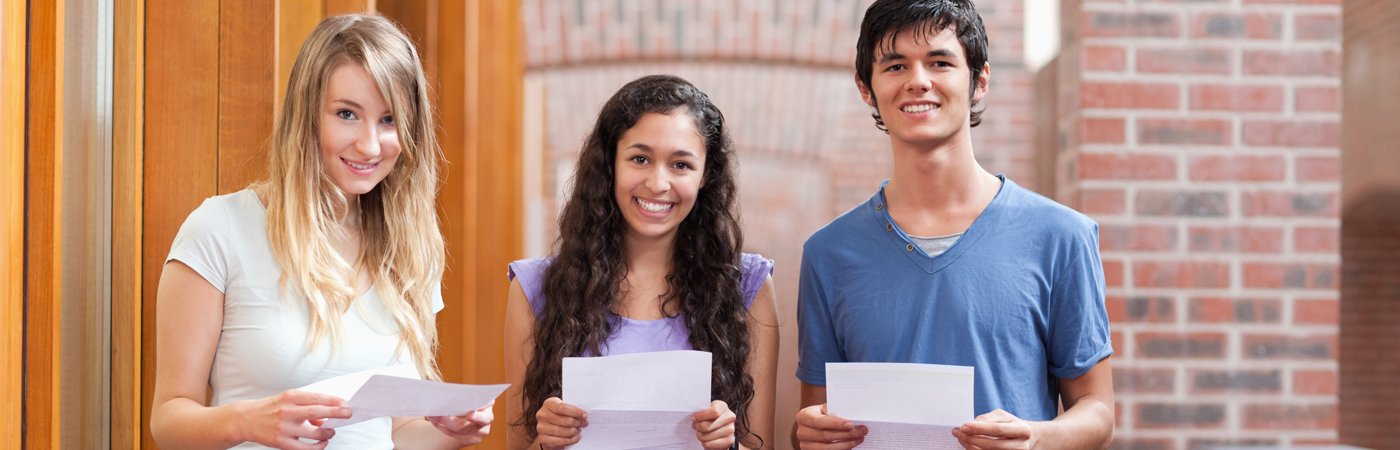 Students standing together, smiling and holding their exam result sheets.