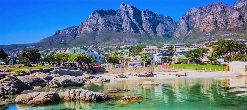 Scenic view of a beach and buildings in Cape Town with Table Mountain in the background.