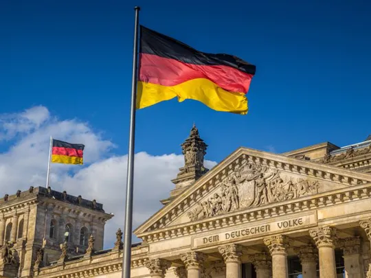 The German flag at full mast infront of an old German building.