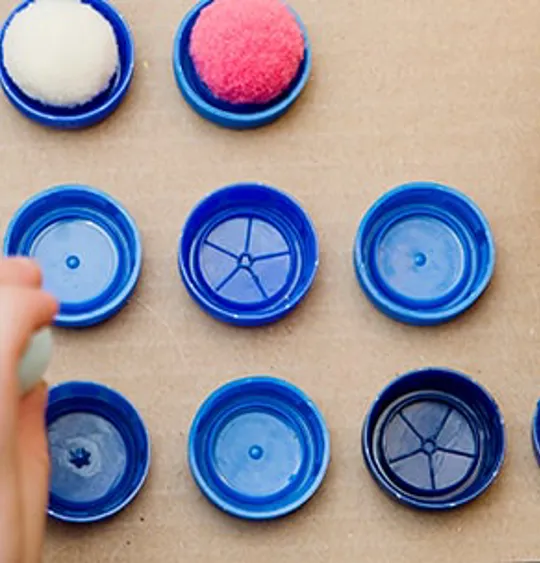 Child sorting colourful pom-poms into numbered bottle tops as part of a hands-on maths activity