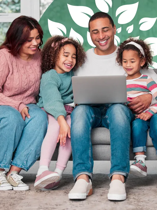 Parents and two young daughters gathered on the sofa enjoying screen time together.