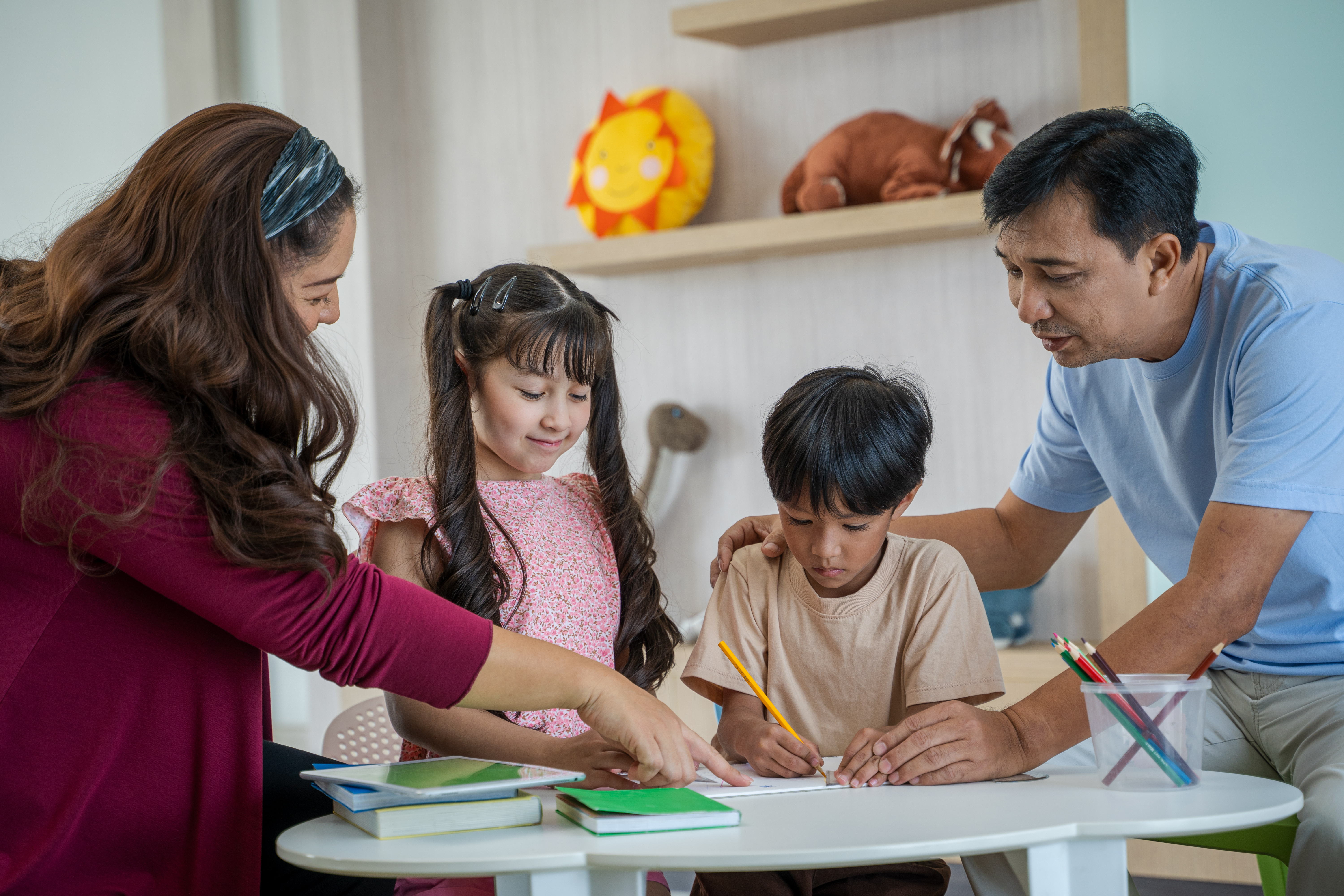 Parents guiding their young children through a learning activity at home.