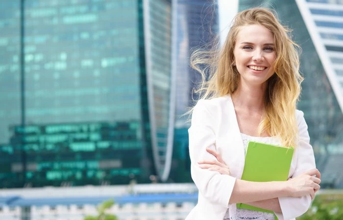 Young woman stood outside tall city skyscapers. 