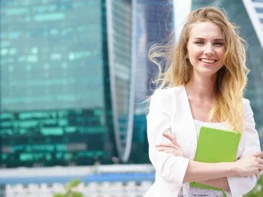 Young woman stood outside tall city skyscapers.