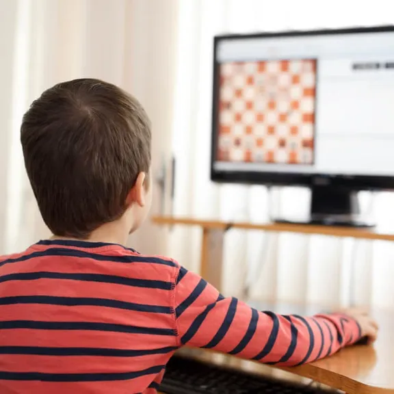 Young child playing chess on the computer.