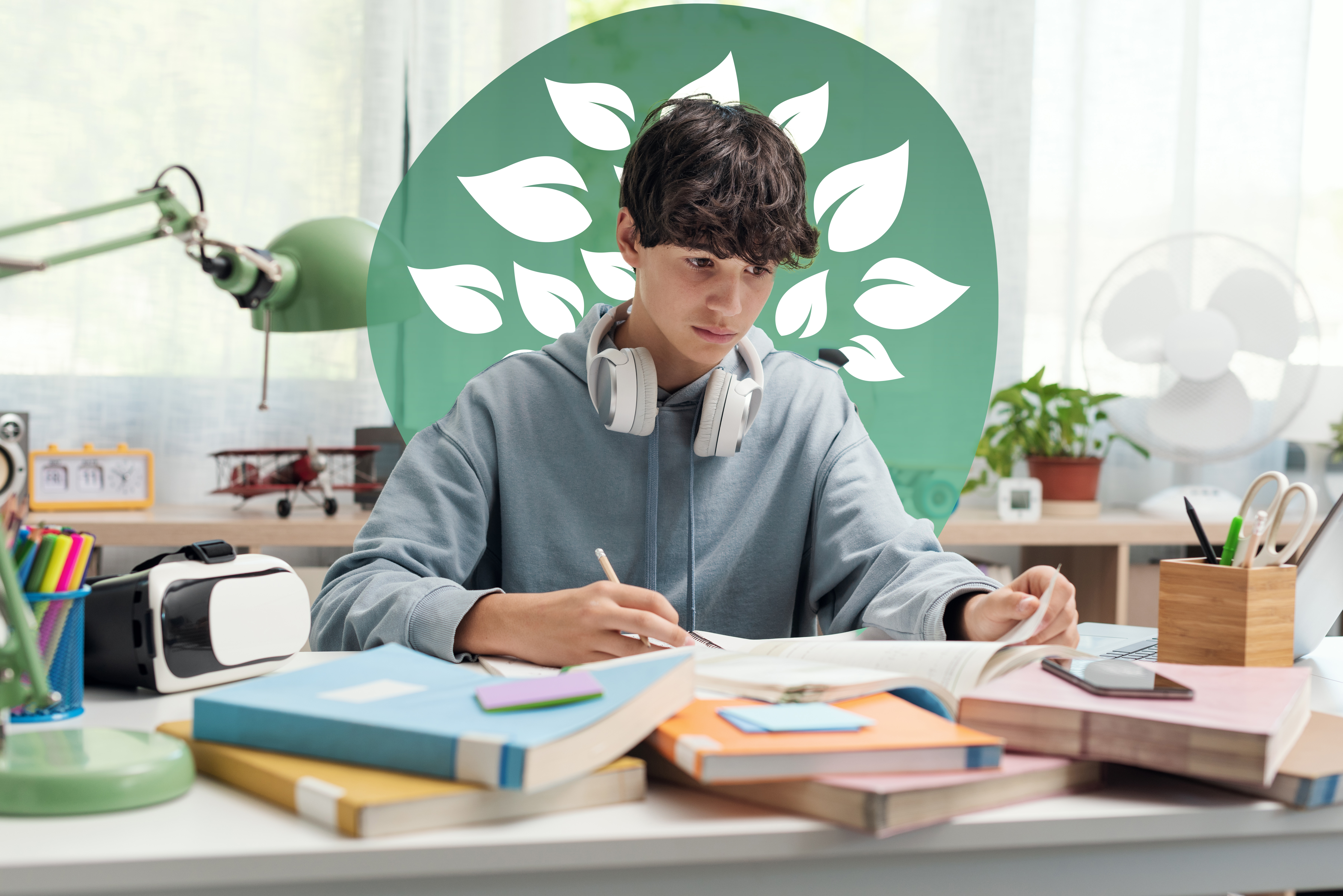 A young person with headphones around their neck sits at a cluttered desk, intently writing in a notebook and surrounded by textbooks, studying hard for GCSE mock exams.