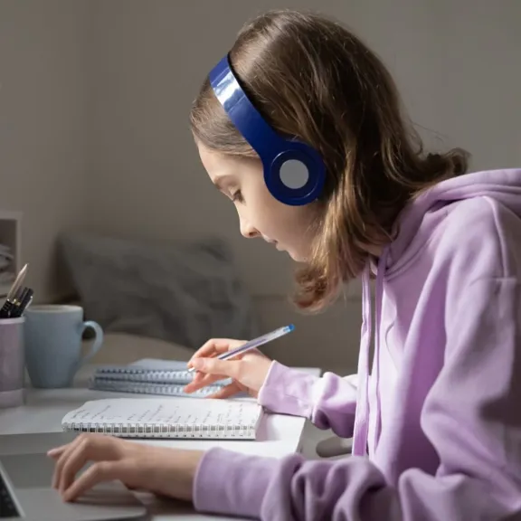 Teen student studying at desk wearing headphones.