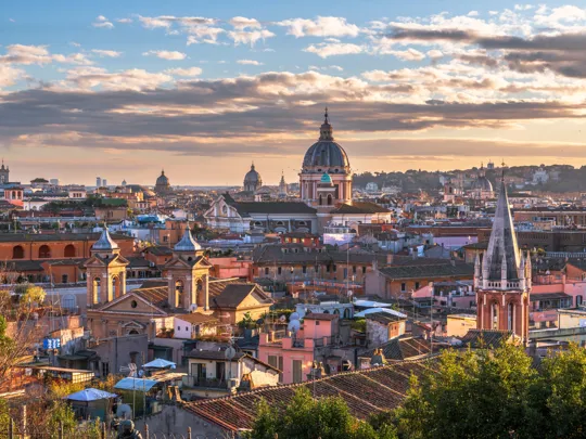 Rome cityscape at sunset with domed churches, terracotta rooftops and spires