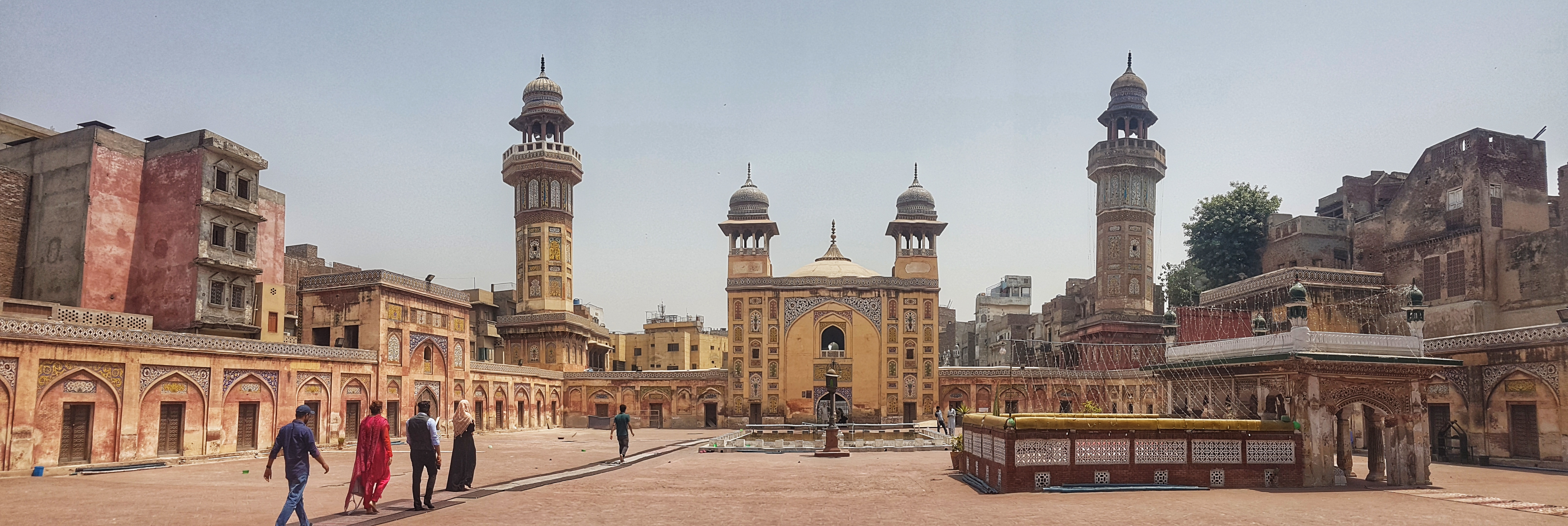 Historic mosque and courtyard in Lahore, Pakistan with people walking through the complex.