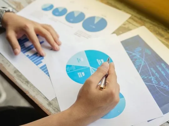 An individual analysing coloured data charts for business purposes.