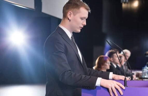 A country leader preparing to speak on a panel of other politicians. 