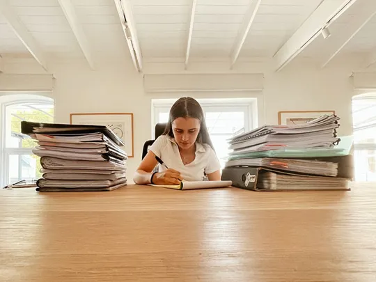 Gabrielle studying, surrounded by books and files.