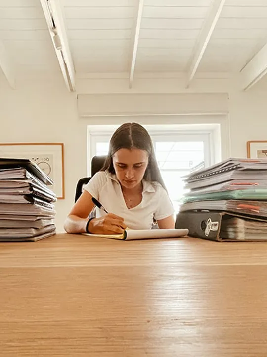 Gabrielle studying, surrounded by books and files.