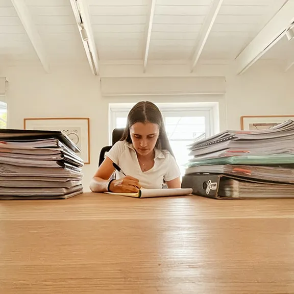 Gabrielle studying, surrounded by books and files.